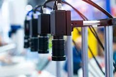 Row of industrial machine vision cameras mounted on production line